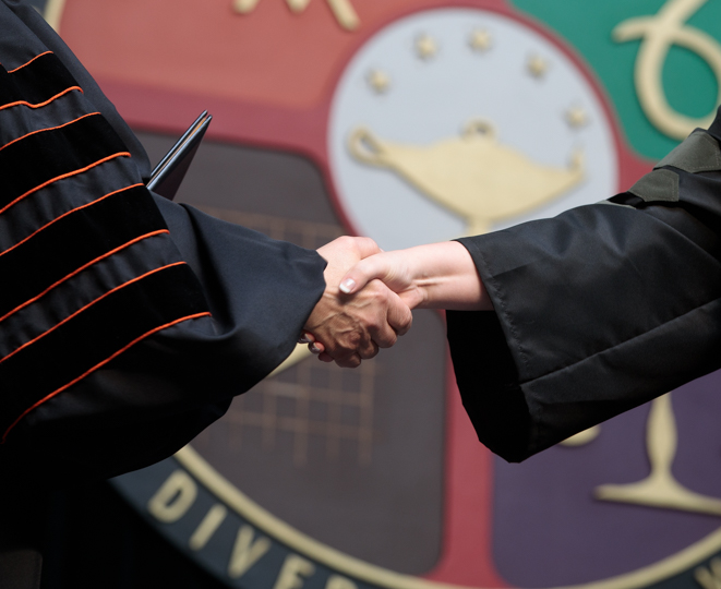Handshake in front to the  University seal